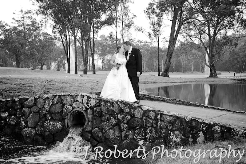 Bride and groom kissing on a bridge over lakes at Riverside Oaks Golf Course - wedding photography sydney